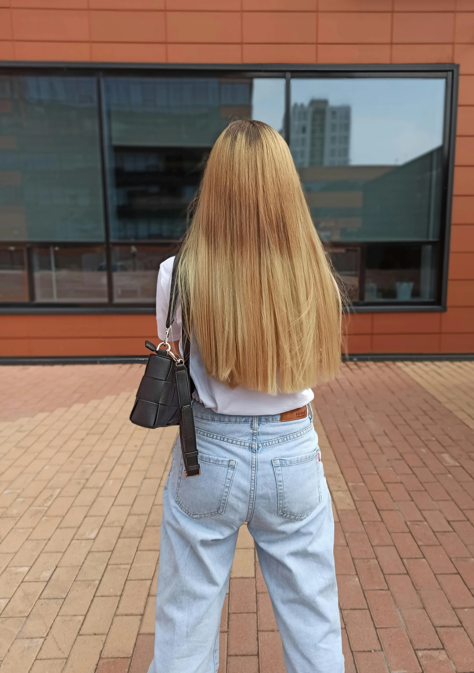 woman with long blonde hair stands at the corner looking out