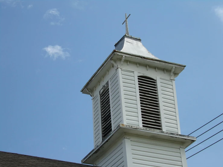 an old white church steeple and a cross at the top