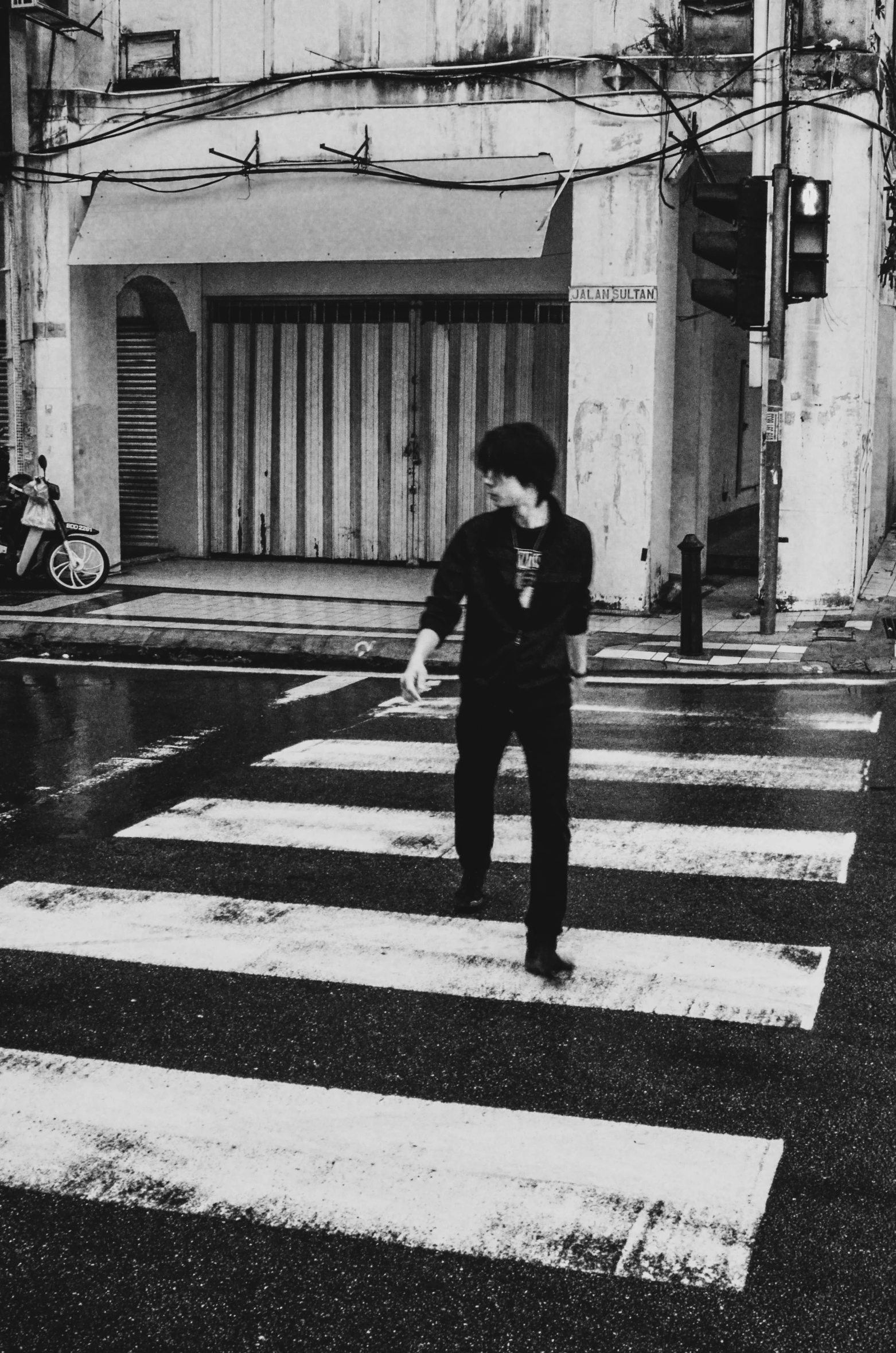 black and white pograph of a man walking across an urban crosswalk