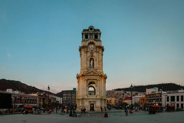 a clock tower sitting in front of a city filled with lots of buildings