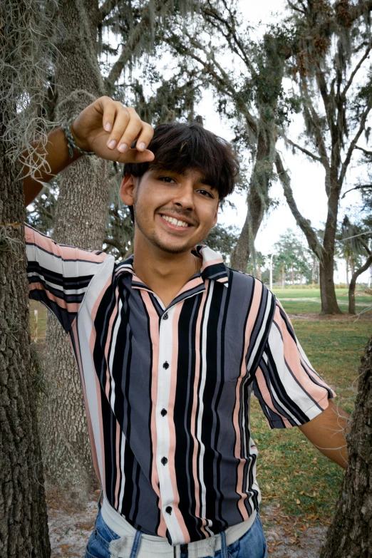 a man standing in front of trees wearing a shirt