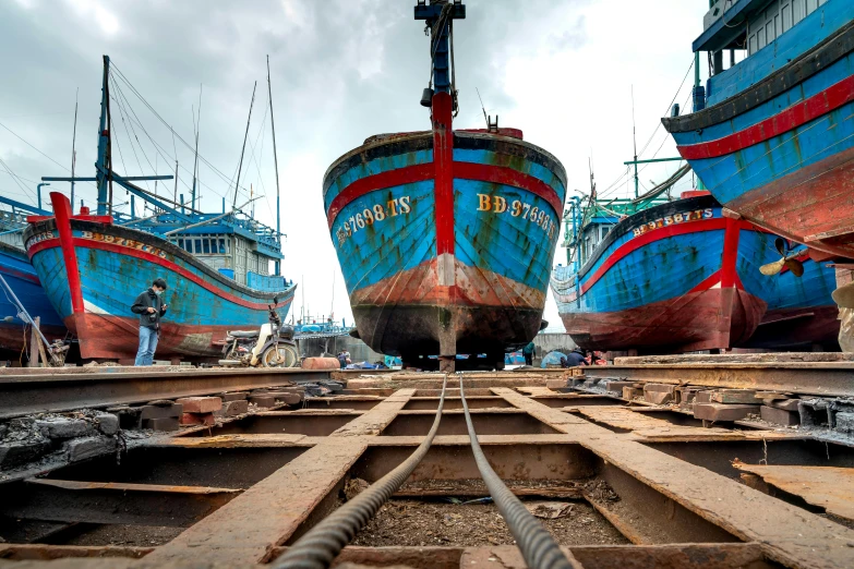 three large blue boats with red stripes docked