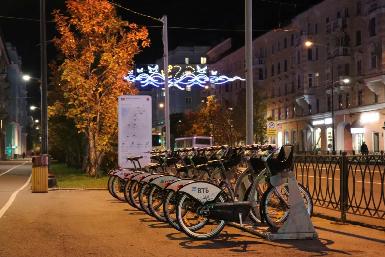 bicycles line up along a bike rack at night