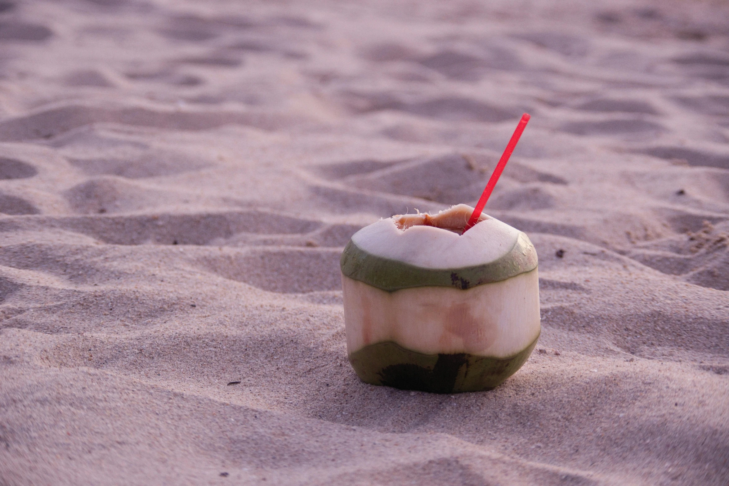 a drink with a straw in the sand