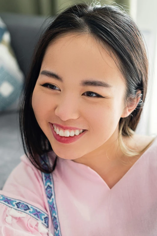 a young woman with an asian smile is wearing a pink dress