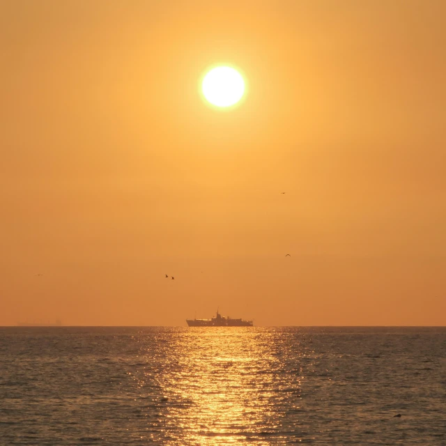 the sun is setting over the ocean and the boat is sailing in the distance