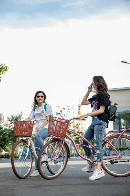 two women riding bikes down a street in front of another woman