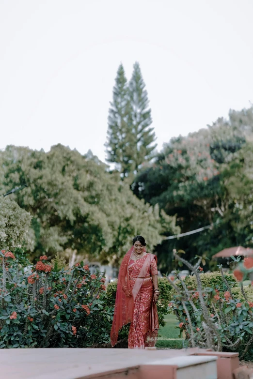 a beautiful young woman in red dress standing next to some trees