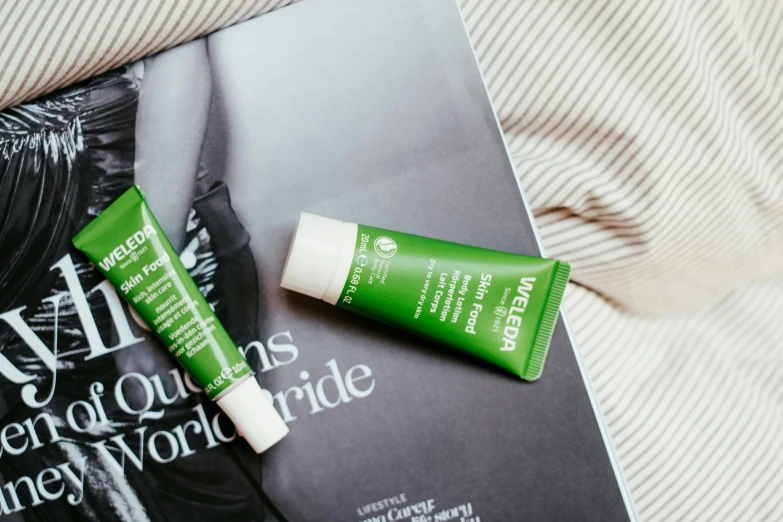 two tube of vitamin - based sunscreens, one is next to the other on top of an open book