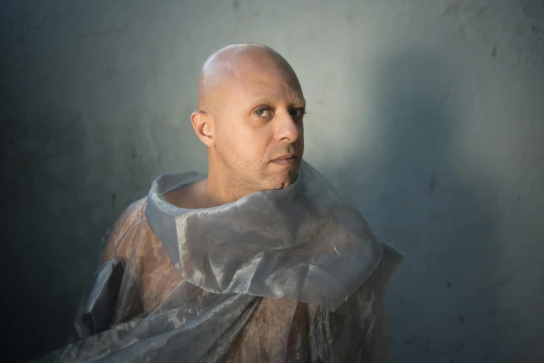 a bald man wearing a gray shirt