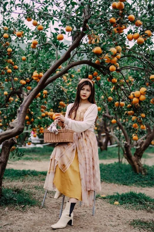 a woman stands in front of a peach tree