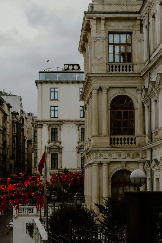 the street is filled with buildings and tall red flags