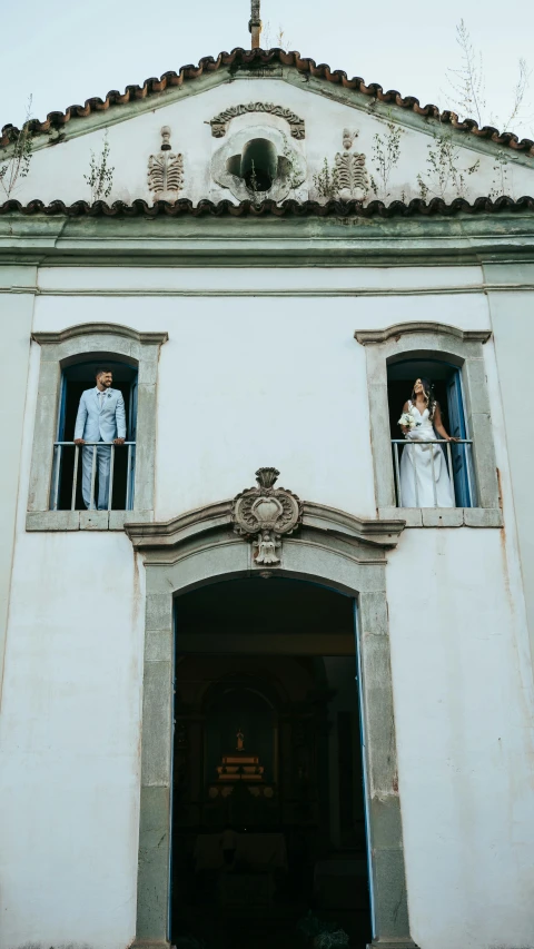 a couple in the window watching another couple on their wedding day
