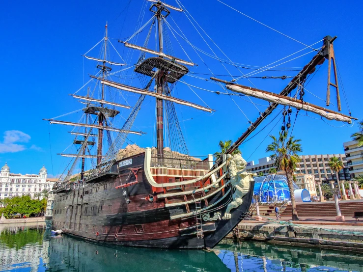 a pirate ship moored on a harbor with the city in the background