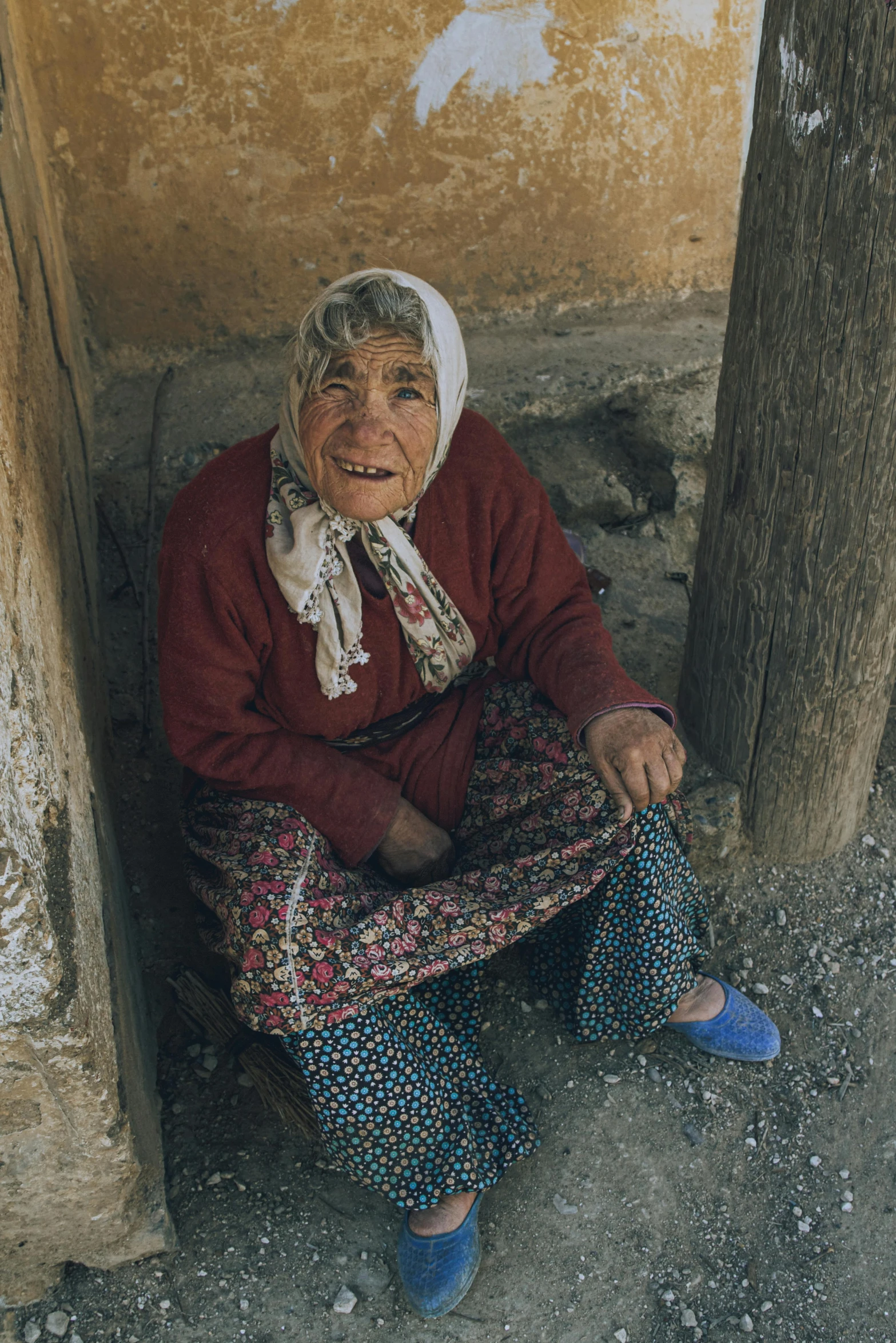 an old woman is sitting next to a tree