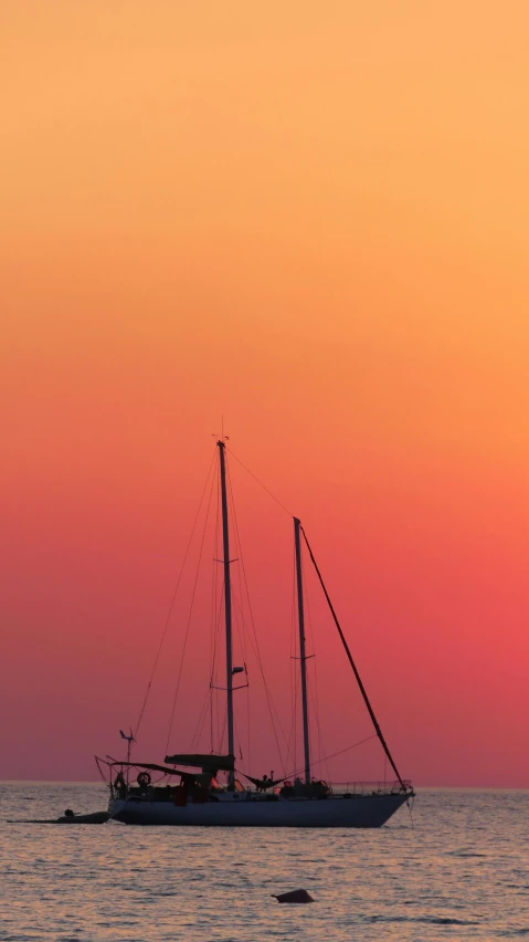 a sailboat floating in the ocean during sunset