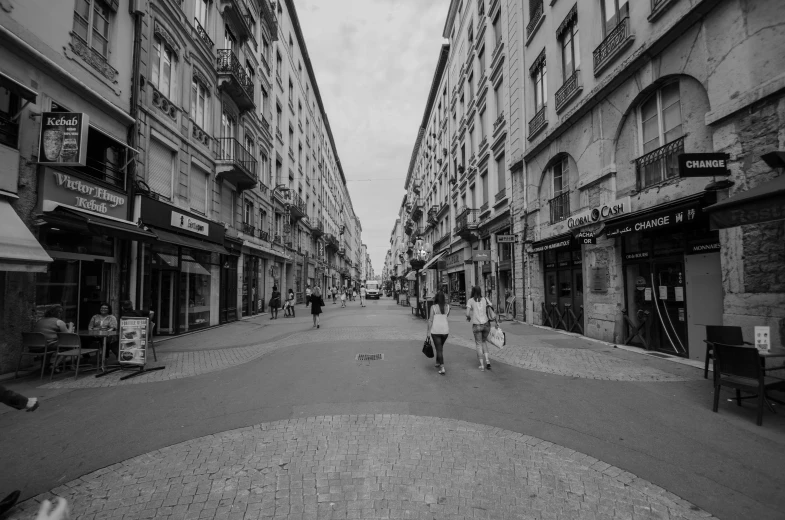 there is a narrow street that has little people walking down it