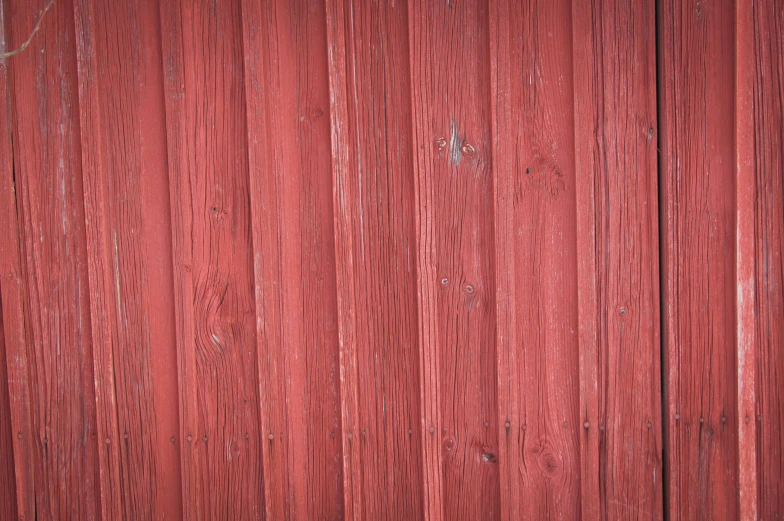 a red barn with rough wooden boards has a knot at the bottom