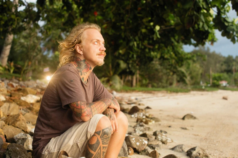 a man is sitting on rocks near the water