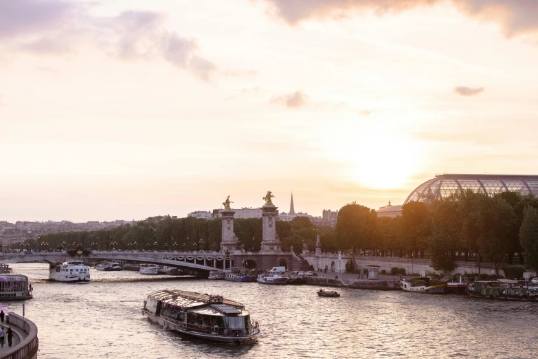 boats on the river in front of a bridge at sunset