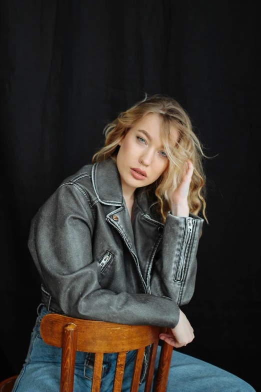 a woman wearing jeans sitting in a chair