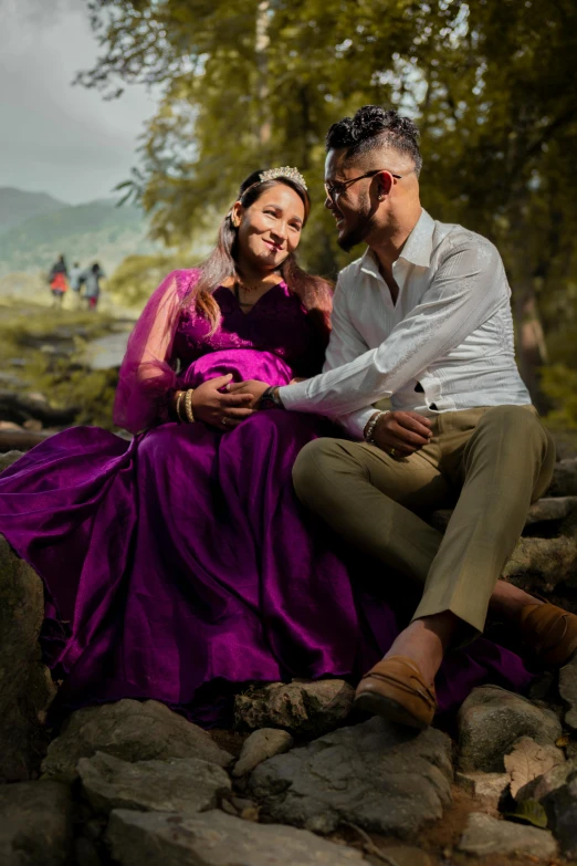 a man and woman wearing formal attire sitting on rocks