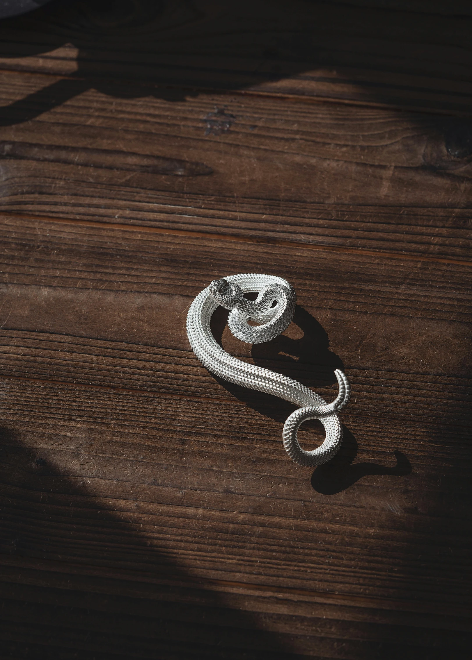 a coiled rope on wooden table in sunlight