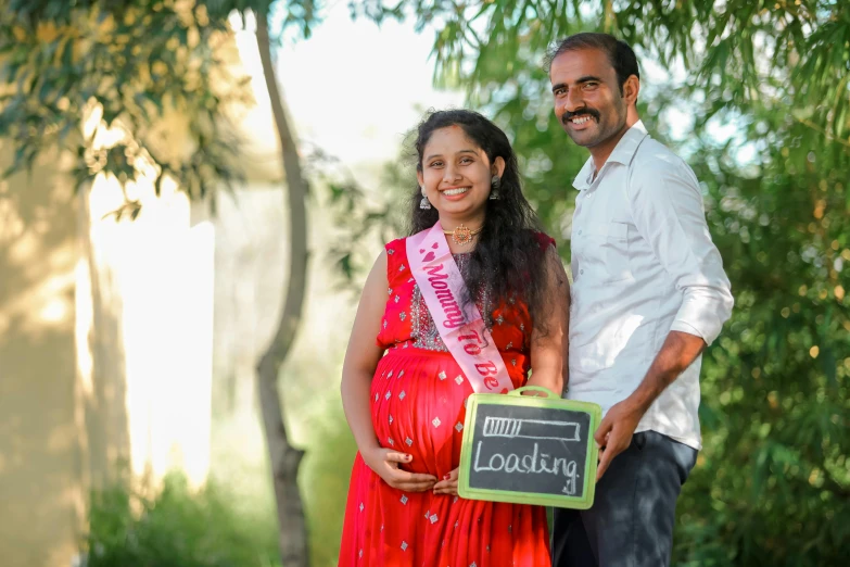 two adults posing for the camera while a man holds a sign