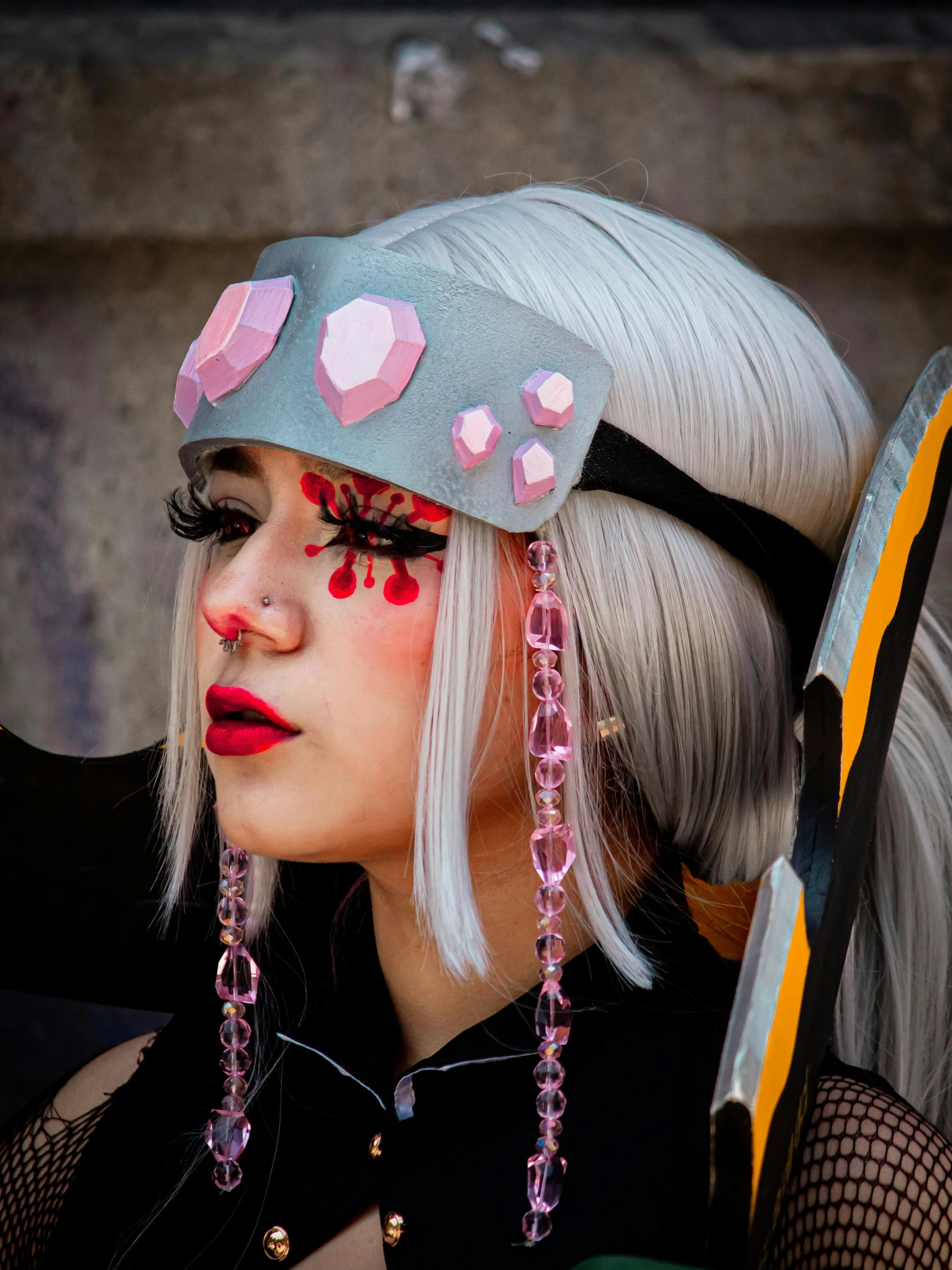 a woman with blond hair and bright makeup wears an unusual hat with flowers