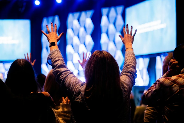 many people are raising their hands in a church