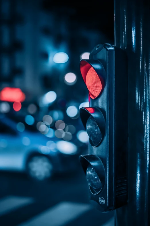 a close up of a traffic light with cars in the background