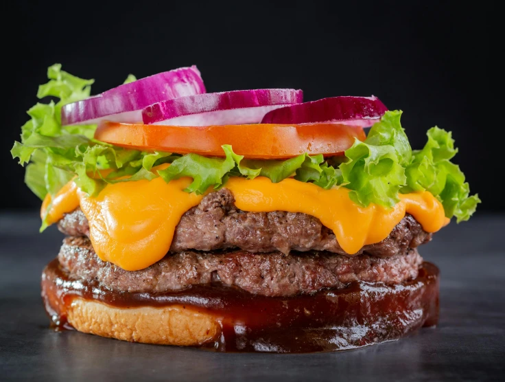 a hamburger with onions, lettuce and dressing on top