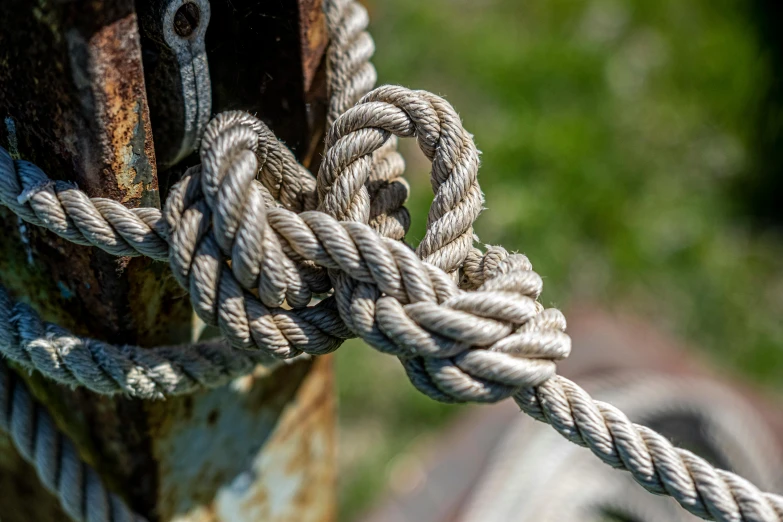 a rope tied to the pole with a rusted metal latch