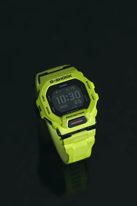 a green watch on a black surface with light reflection