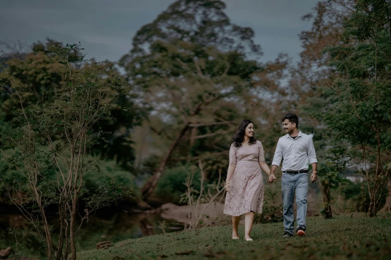 man and woman walk side by side through a field holding hands