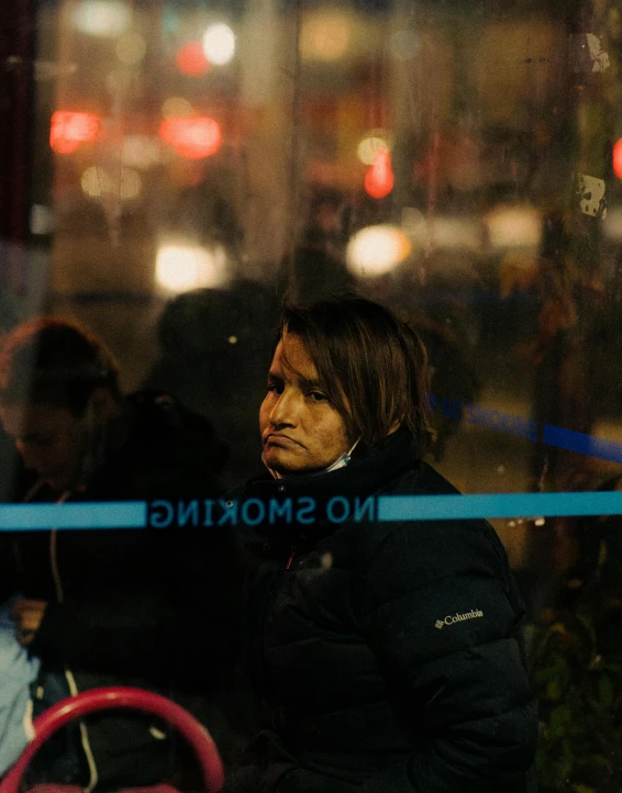 woman in dark clothes standing by blue ribbon looking off into distance