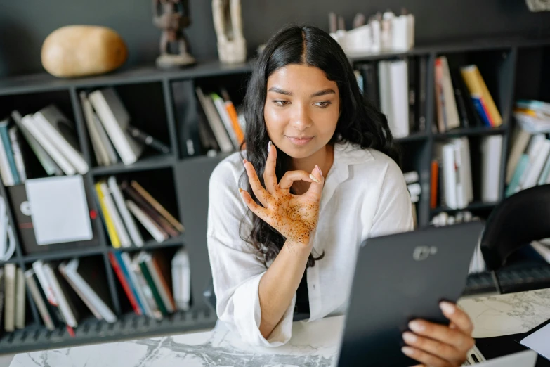 woman sitting in front of a laptop computer holding up her hands