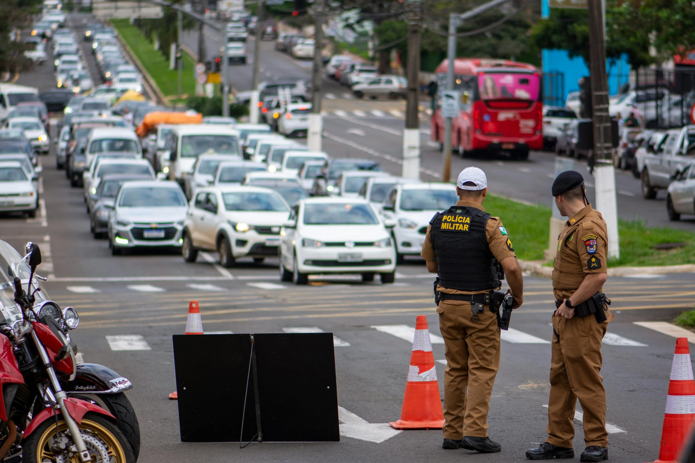 two officers standing by their bikes near a street filled with cars