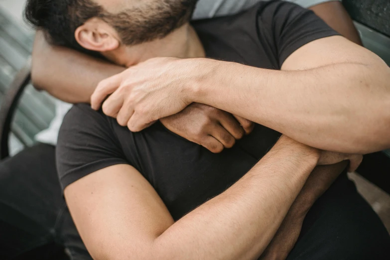 man with beard sitting on bench hugging arm