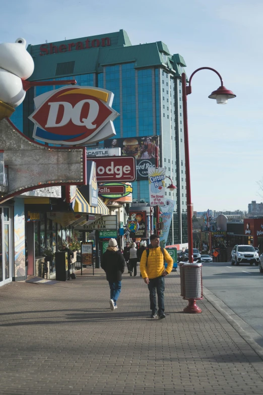 a man and woman walk down a bricked sidewalk