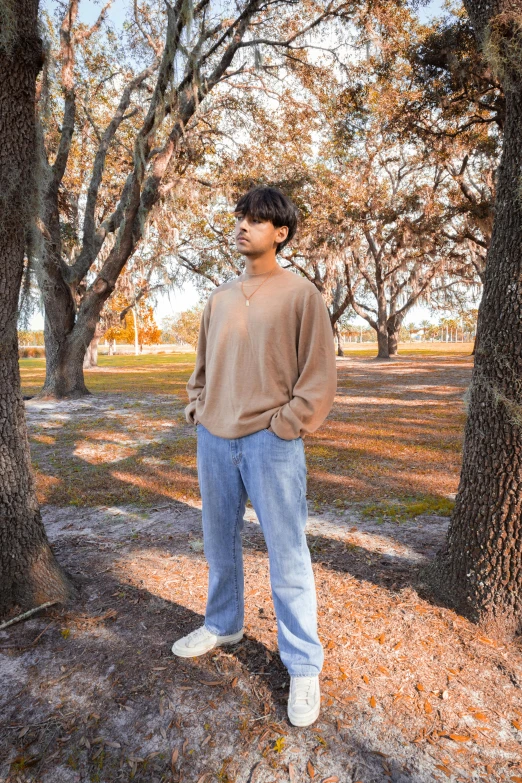 a young man is standing in front of the trees