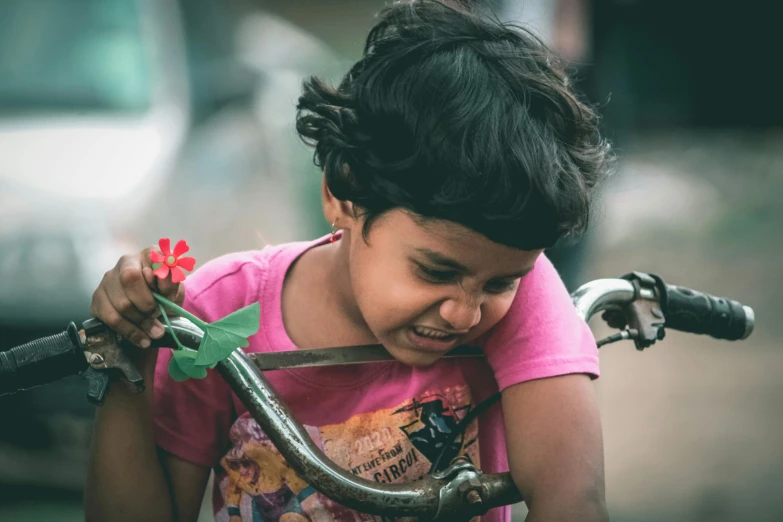 a small child with a bike handle holding onto a flower