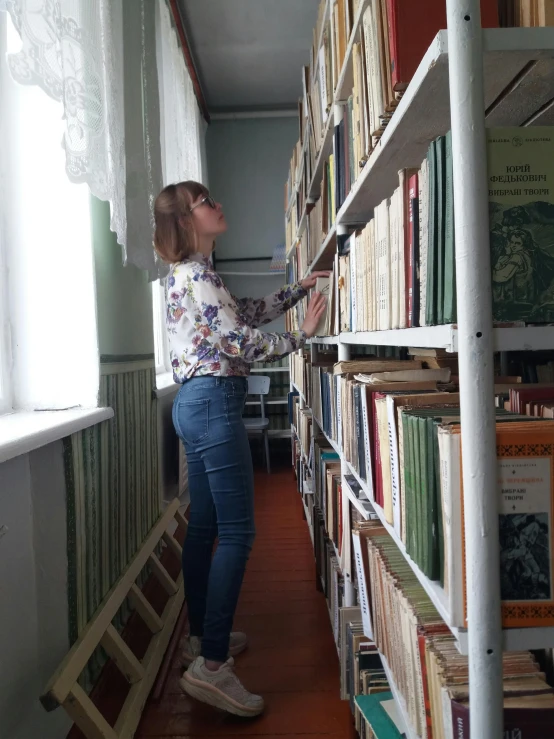 a woman standing in a book room holding a ladder
