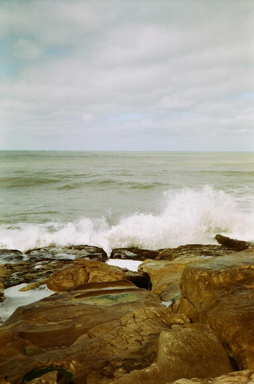 a surfboarder sits on the edge of the waves in front of a beach