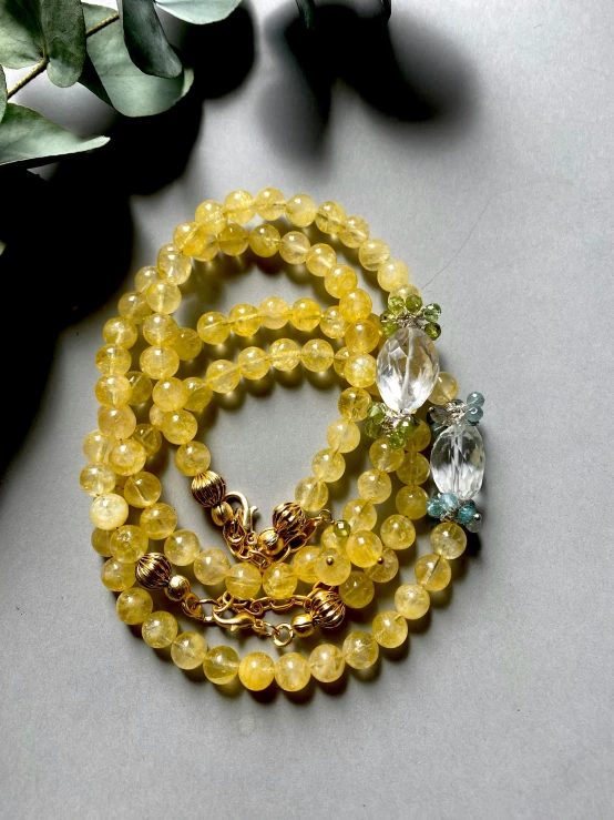 a yellow celet with charms is next to green leaves