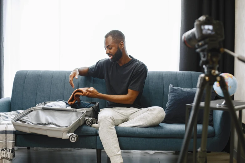 man sitting on a couch with his luggage in front of him