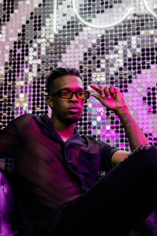 a young man with glasses sitting on a chair