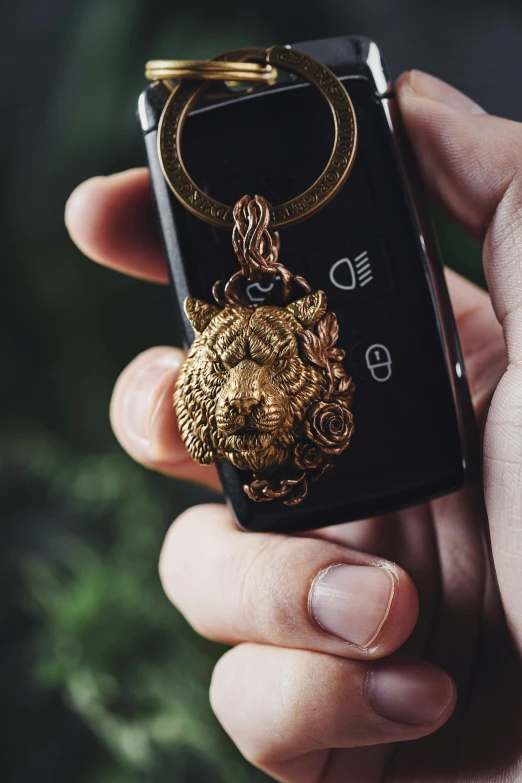 a person holding a black key chain with a gold plated medallion on it