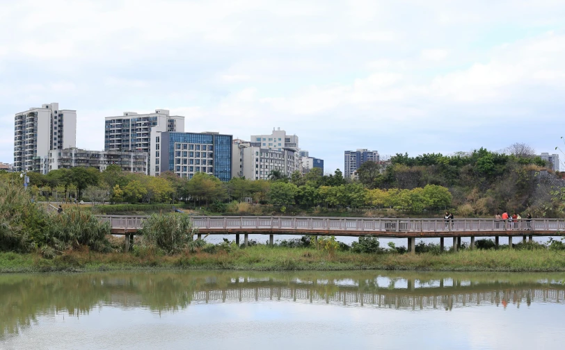 the people are walking across the bridge over the lake