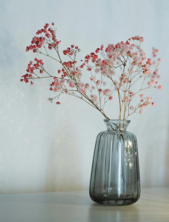 a small vase with red flowers in it sitting on a table